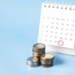 Calendário ao lado de moedas em fundo azul
