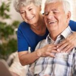 Casal de idosos sorrindo olhando para tela de computador