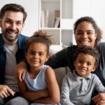 Família de quatro pessoas sentada em sofá posando para foto
