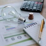 Lâmpada com conta de luz, moedas e calculadora