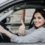 Mulher ao volante fazendo sinal de positivo