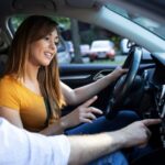 Mulher ao volante sendo orientada por instrutor