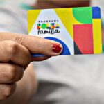 Mulher segurando cartão do Bolsa Família