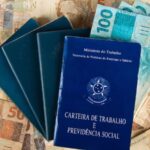 Notas de cinquenta reais por baixo de carteiras de trabalho