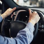 Pessoa com as mãos no volante de carro