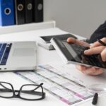 Pessoa com calculadora, contas e notebook