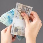 Pessoa contando notas de cem e duzentos reais