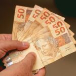 Pessoa segurando notas de cinquenta reais