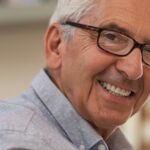 Senhor grisalho de óculos sorrindo e posando para foto