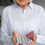 Senhora grisalha segurando cartelas de remédios