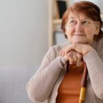 Senhora idosa apoiando o queixo em bengala