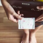 Zoom em mulher abrindo a bolsa e retirando absorvente higiênico